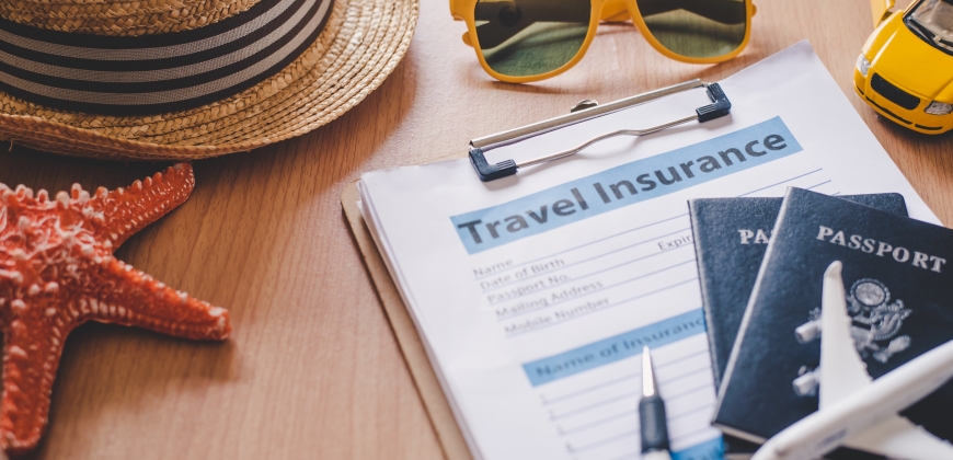 Picture of passports, travel insurance papers, sunglasses, a starfish, and a hat