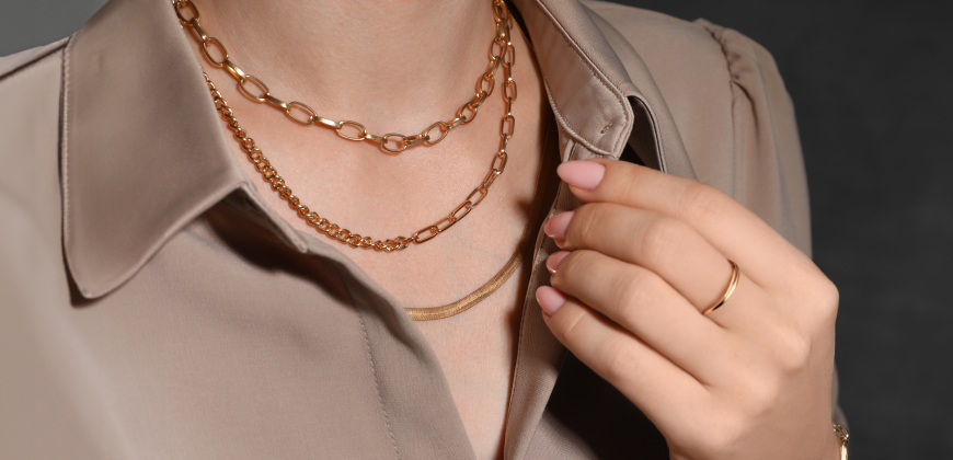 Person wearing three gold necklaces and a gold ring