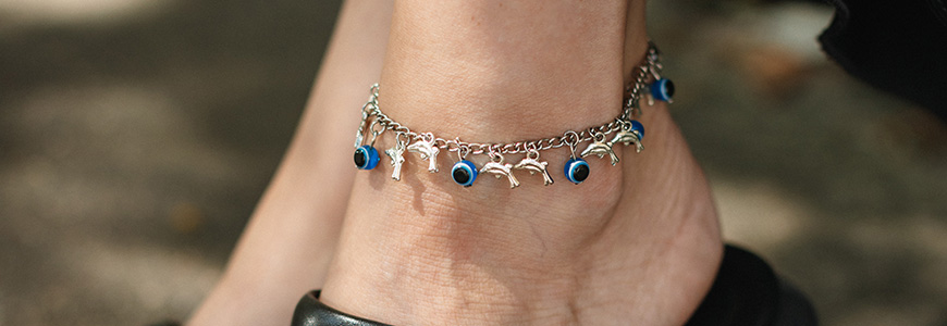 woman with black sandal pumps wears anklet with blue and dolphin charms