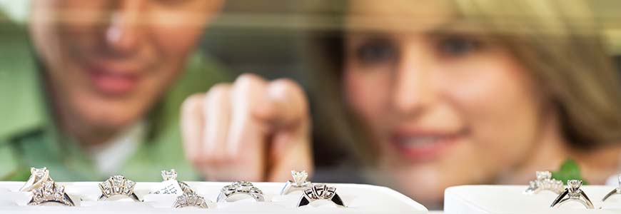 brunette man and blonde woman look inside jewelry case full of rings 
