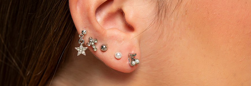 close up of woman's ear with multiple ear piercings lining her ear 