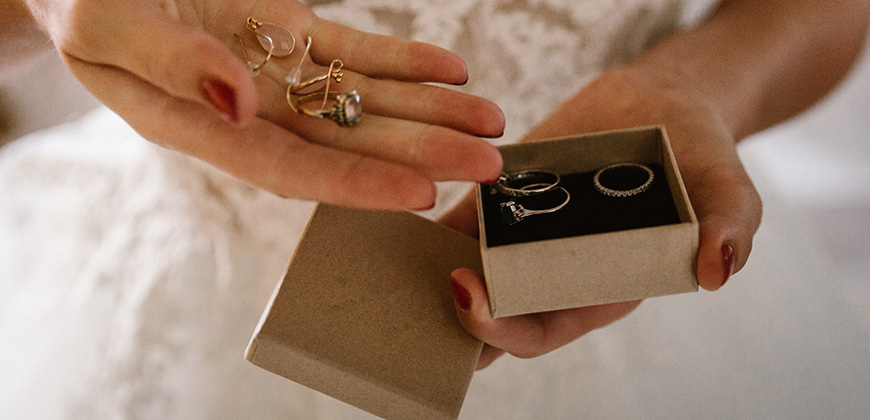 woman holds significant wedding jewelry in hand while wearing wedding dress