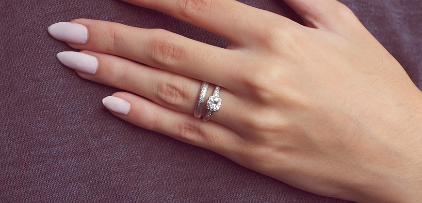 woman's hand with large diamond ring and silver wedding band