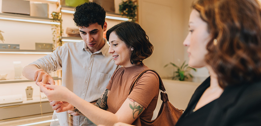 couple looks at diamond jewelry alongside jeweler
