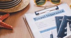 Picture of passports, travel insurance papers, sunglasses, a starfish, and a hat 