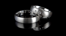 Two men's silver wedding bands on a black background