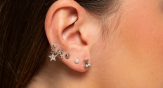 close up of woman's ear with multiple ear piercings lining her ear 