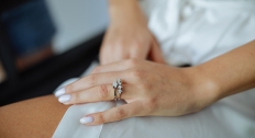 woman rests hand with large engagement ring on it on thigh