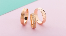 set of three rose gold rings on a pink background