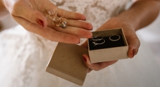 woman holds significant wedding jewelry in hand while wearing wedding dress