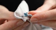 person cleaning white gold and topaz ring with cloth