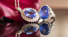 sapphire ring and sapphire necklace sit on reflective table